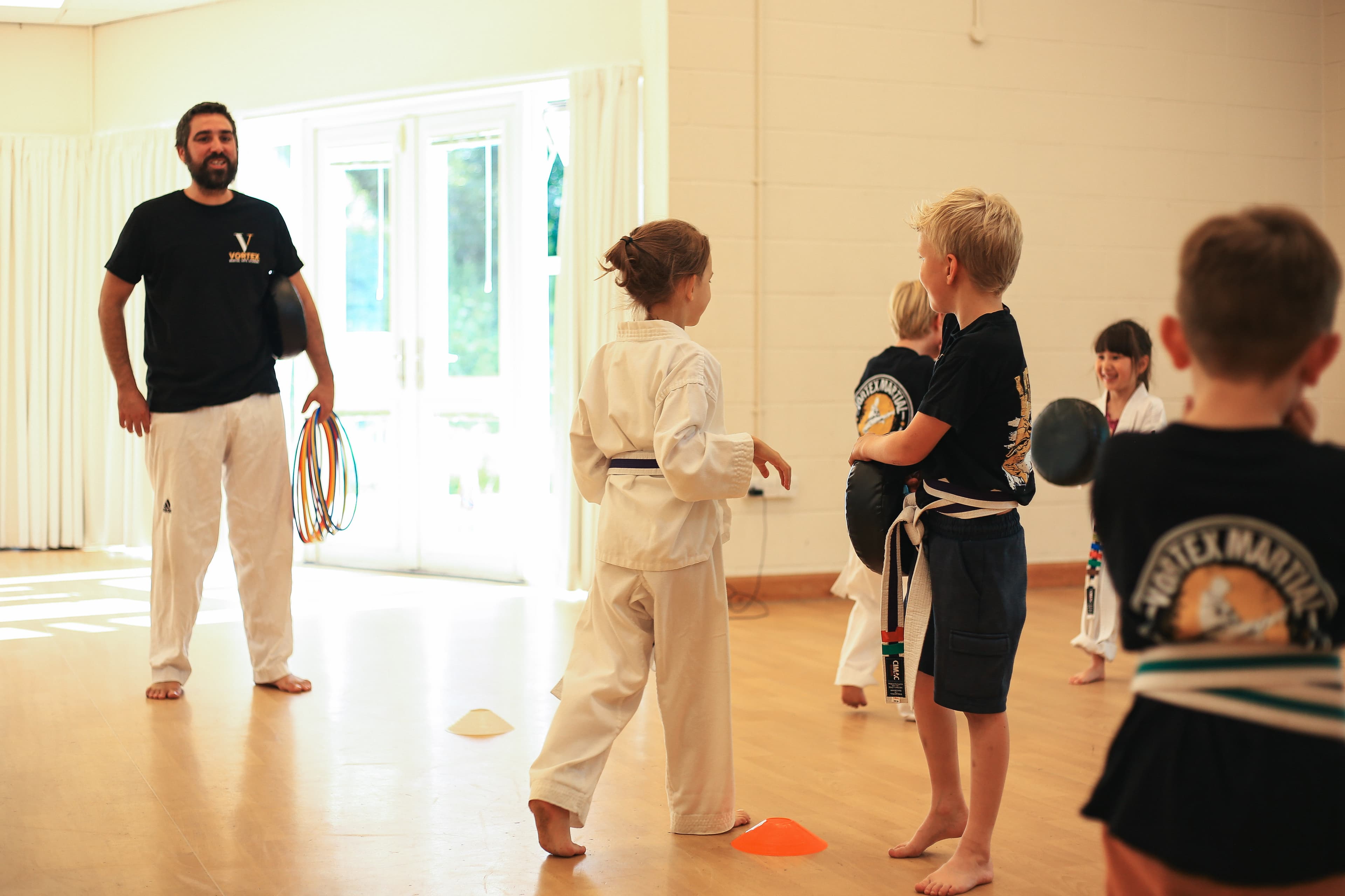 Cadets class at Vortex Martial Arts Academy, coach gathering students for a games-led technique drill