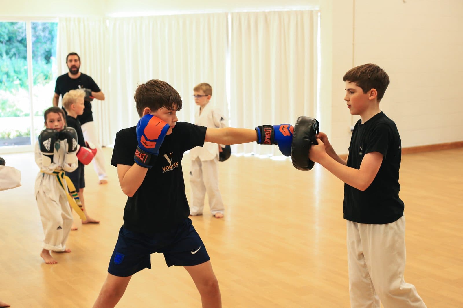 Students aged 8 and above in a high-energy kickboxing class at Vortex Martial Arts Academy, Lancaster