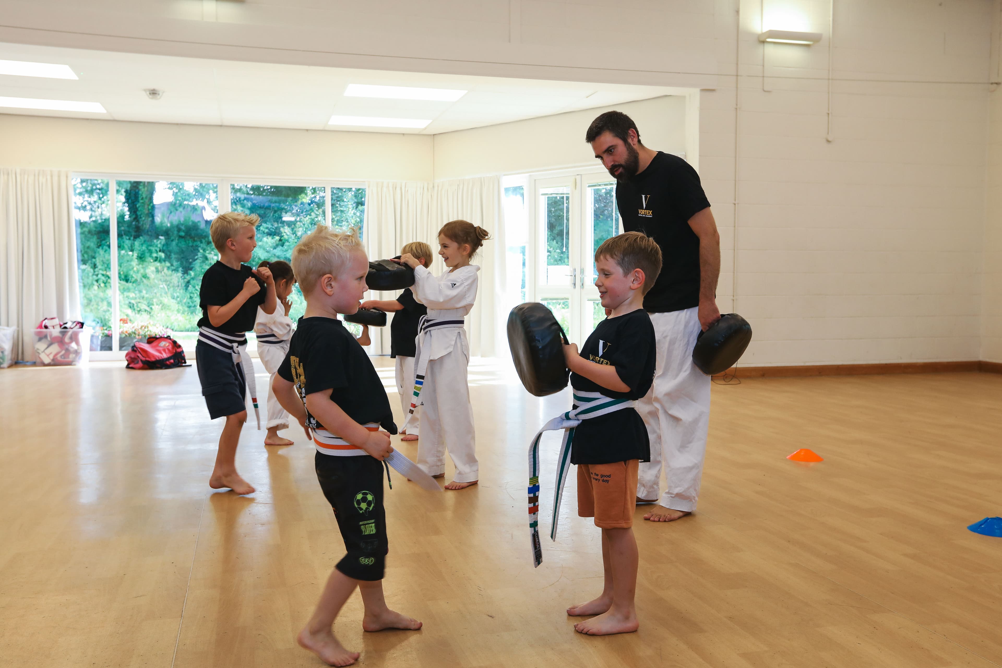 Young children doing pad work in a Dragons martial arts class at Vortex Martial Arts Academy