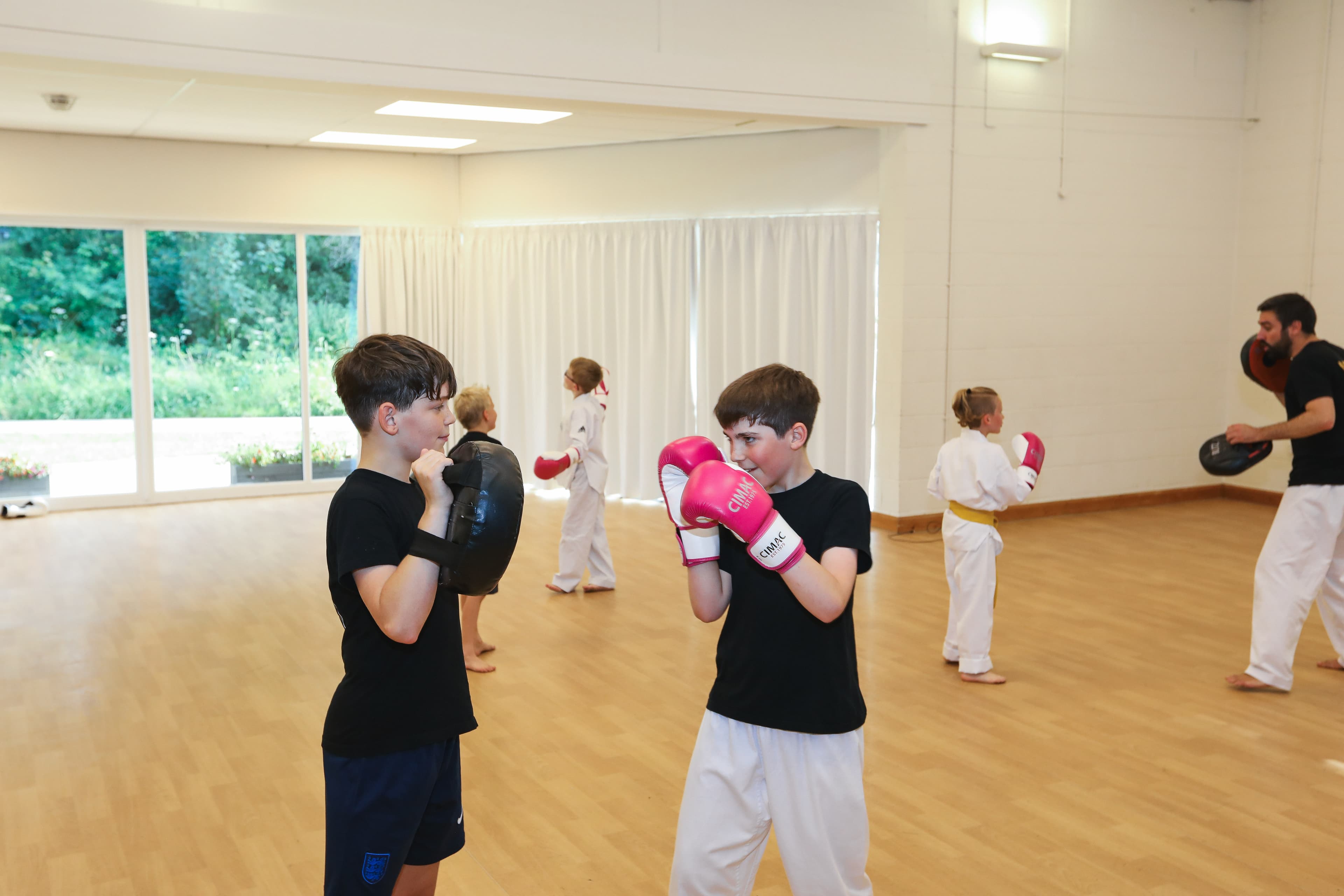 Kickboxing class at Vortex Martial Arts Academy, students working pad drills with the coach
