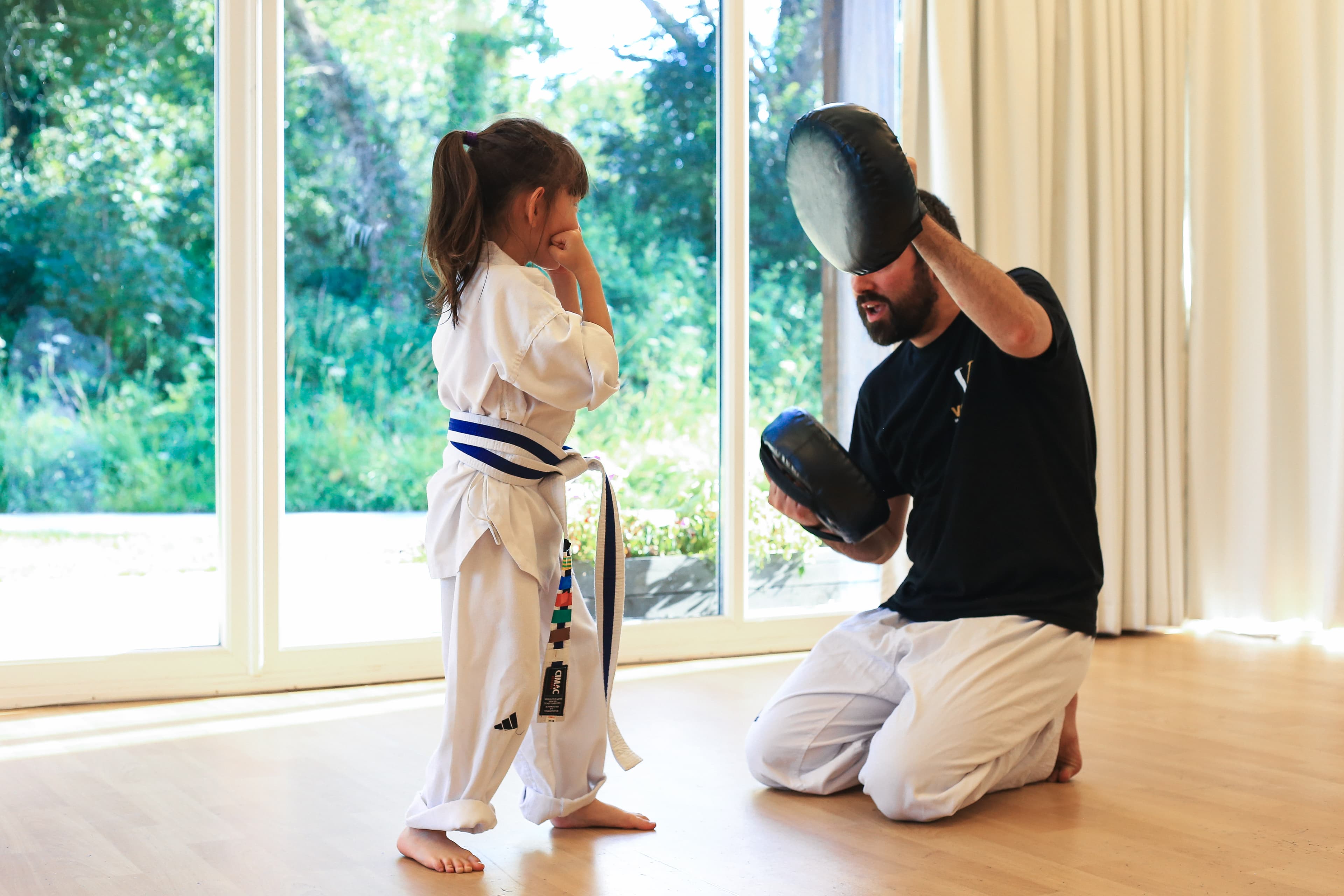 Andy Griffiths kneeling with a young student at Vortex Martial Arts Academy